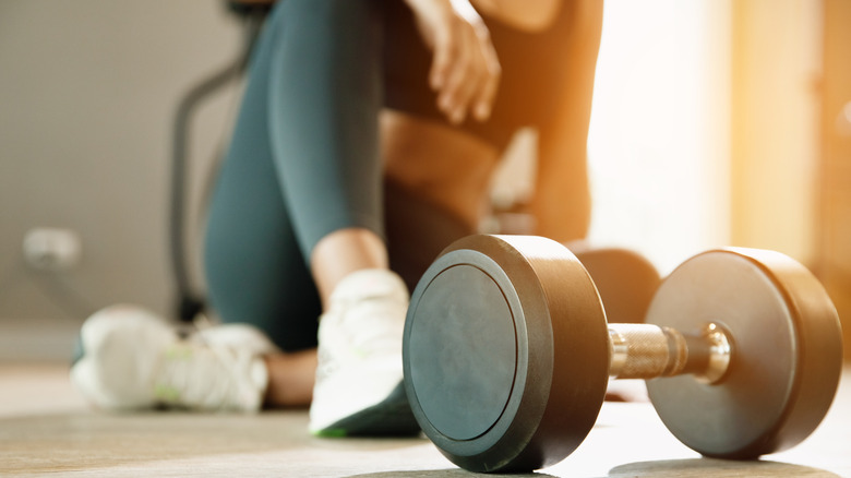 Vrouw silhouet achter vrije gewichten