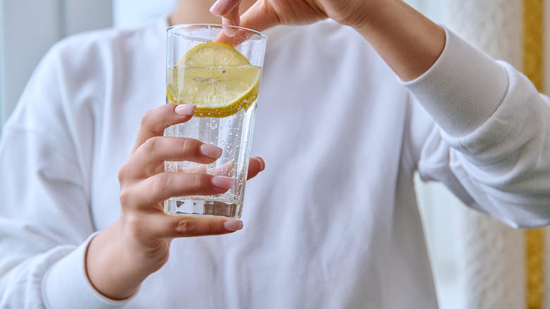 Met de hand uitknijpende citroen in waterglas