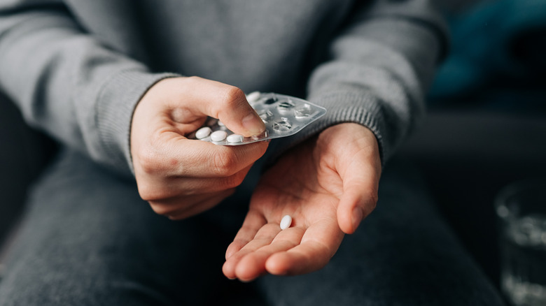 Persoon die antibiotica uit de pilcontainer haalt