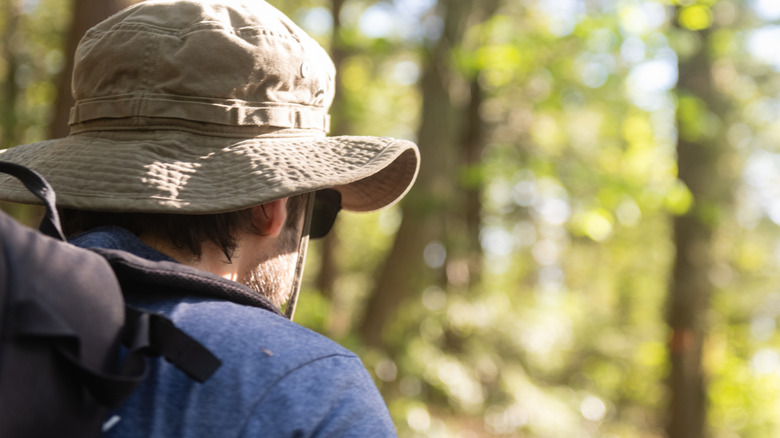 Terug van de mens die hoed en beschermende uitrusting in het bos draagt