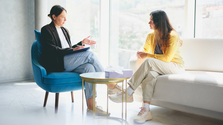 Een vrouw die met haar therapeut praat in een kamer met een groot raam