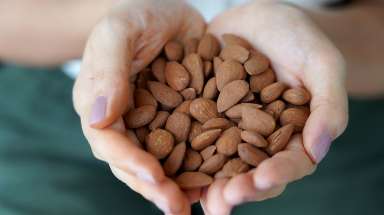 De handen van een vrouw die amandelen vasthouden