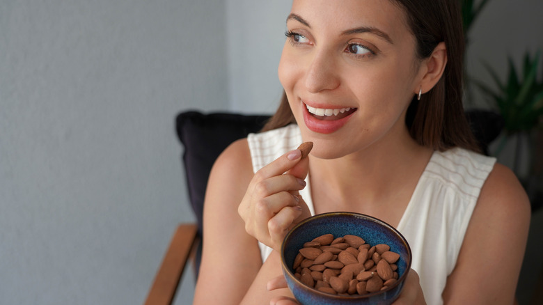 Een vrouw die amandelen uit een kleine kom eet