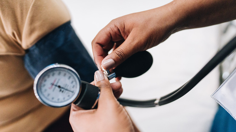 Verpleegkundige hand Putting bloeddrukmonitor op de patiënt