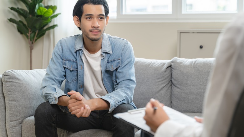 Jonge man die praat met een therapeut of dokter op kantoor