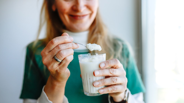 Vrouw met een lepel gewone yoghurt van een glas