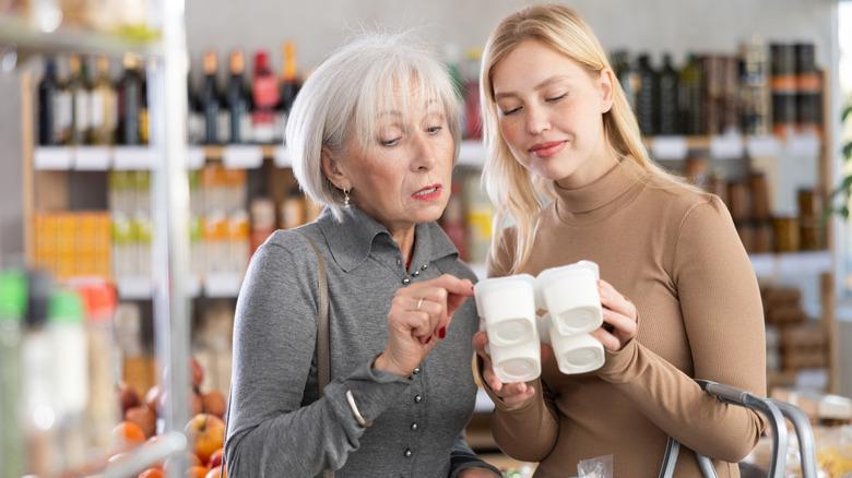Oudere vrouw en jongere vrouw kijken naar yoghurt