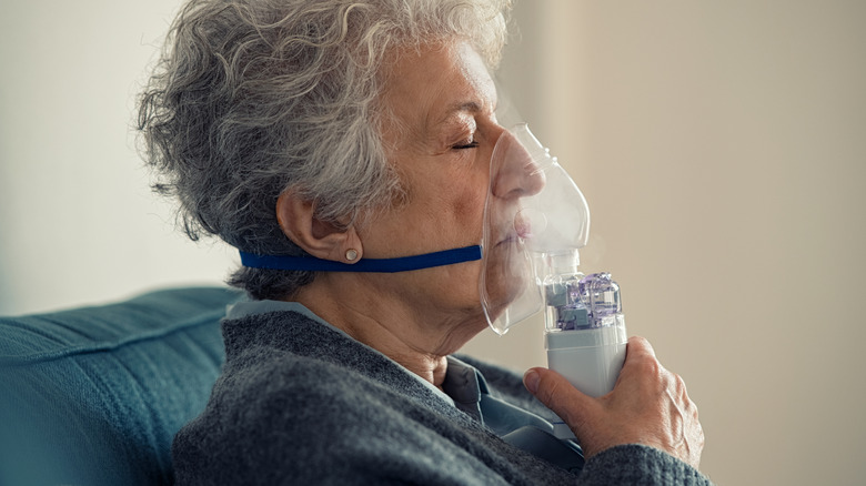 Oudere vrouw ademt thuis door masker