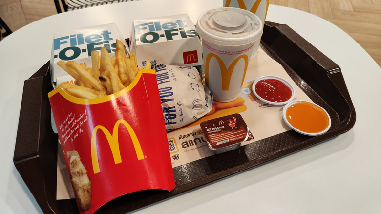 Twee filet-o-fish sandwiches, een kant van friet, een hamburger, frisdranken en dompelende sauzen op een McDonald's Tray