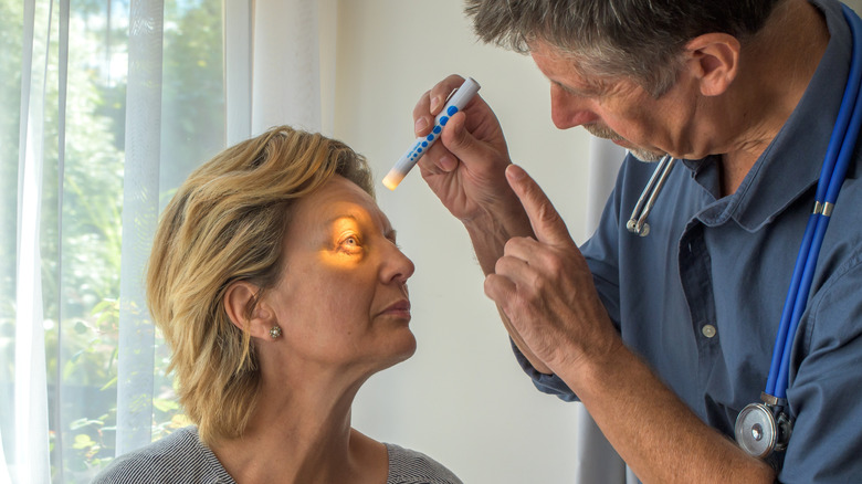 Een oogarts die een klein licht gebruikt om het oog van een vrouw te zien