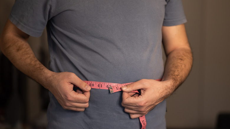 man meet de taille om te zien of hij afgevallen is