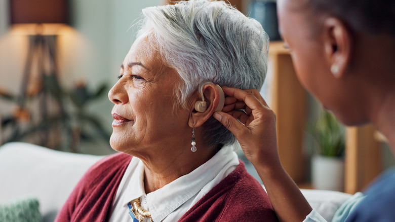 Oudere vrouw met een gehoorapparaat in haar oor gestopt