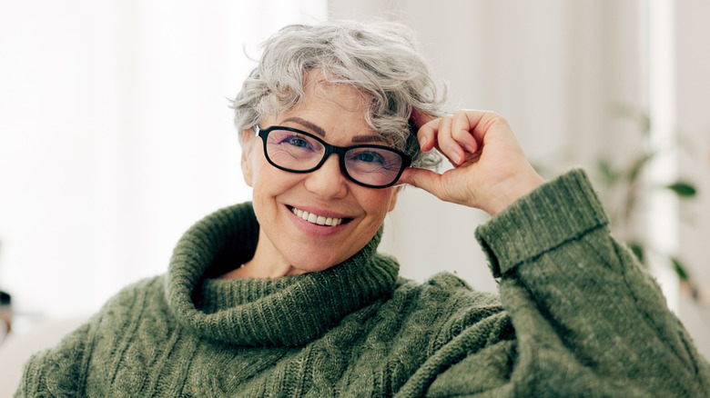 Een slim uitziende vrouw die een bril draagt ​​en haar hoofd aanraakt