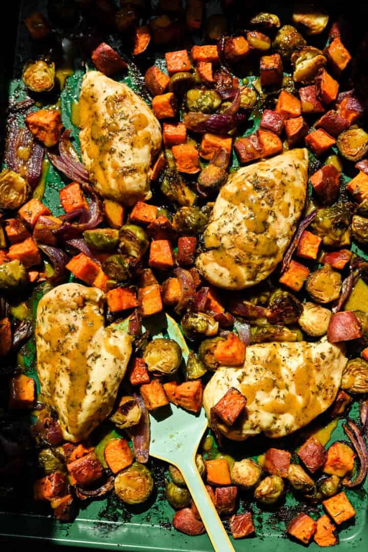 Overhead uitzicht op esdoorn mosterdplaat pan kip met geroosterde herfstgroenten op een groene plaatvorm.