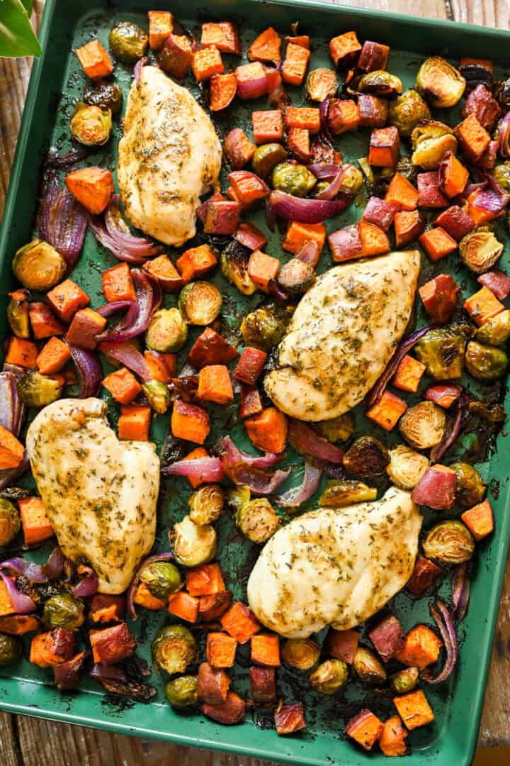 Overhead uitzicht op esdoorn mosterdplaat pan kip met geroosterde herfstgroenten op een groene plaatvorm.