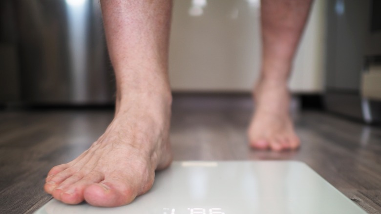 man die op schaal loopt om zichzelf thuis te wegen