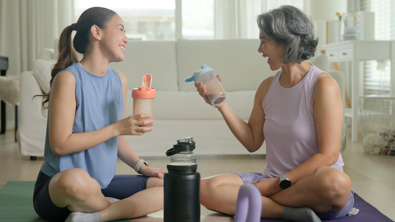 Jonge vrouw en moeder die eiwitten drinken