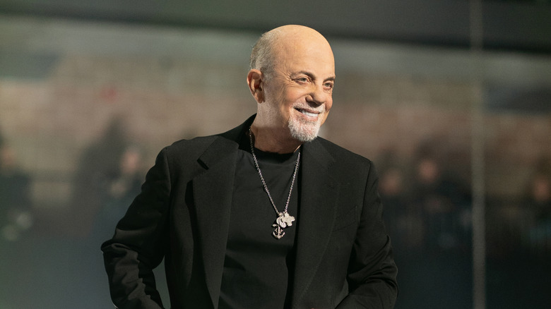 Muzikant Billy Joel glimlacht terwijl hij op het podium staat