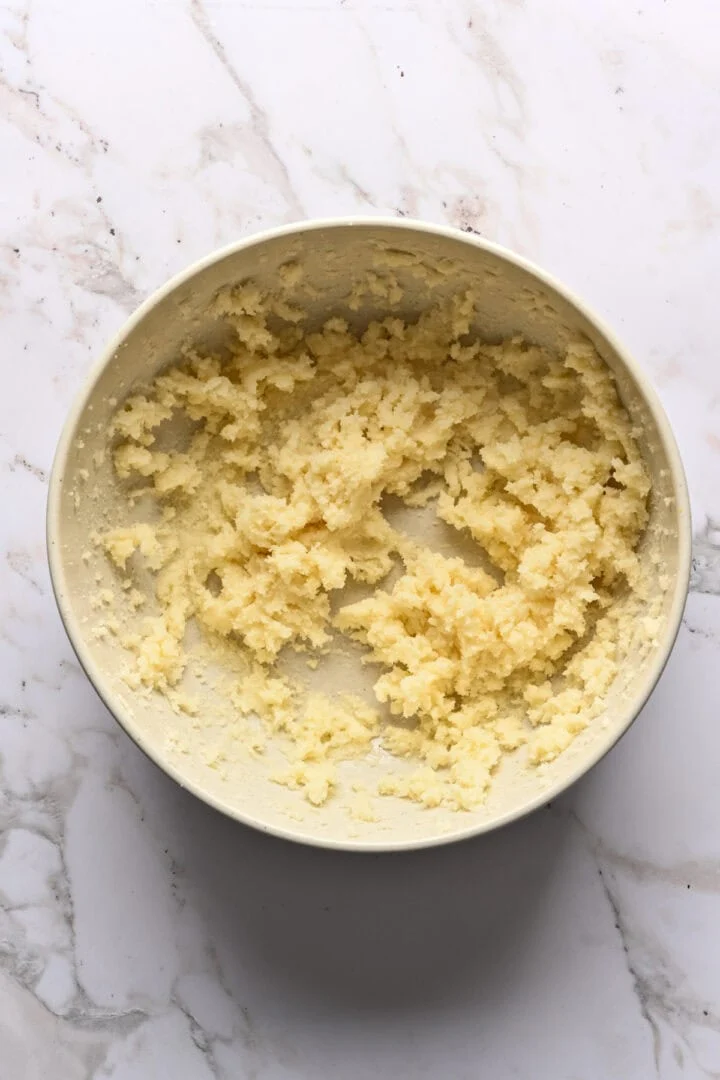 Boter en suiker afgeroomd in een witte mengkom.