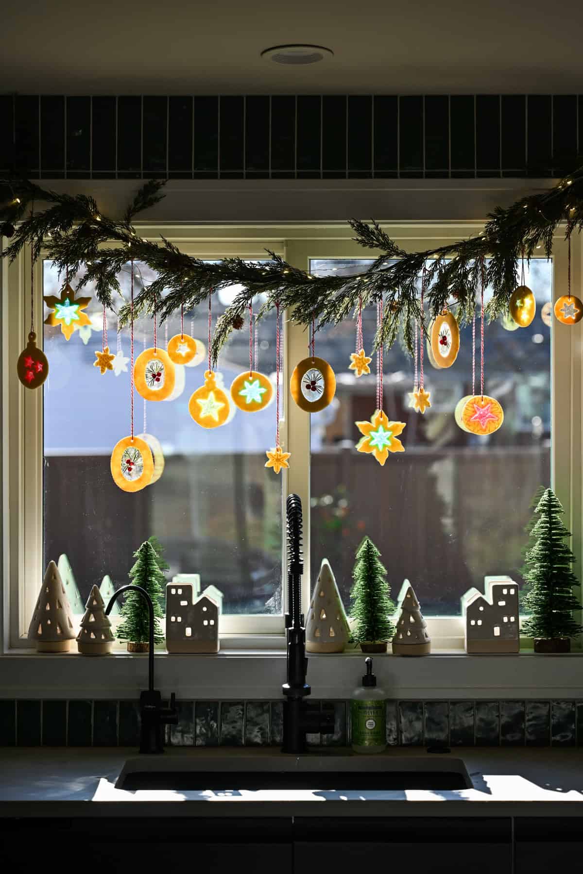 Koekjesversieringen van glas-in-lood hangen aan een slinger boven een aanrecht.