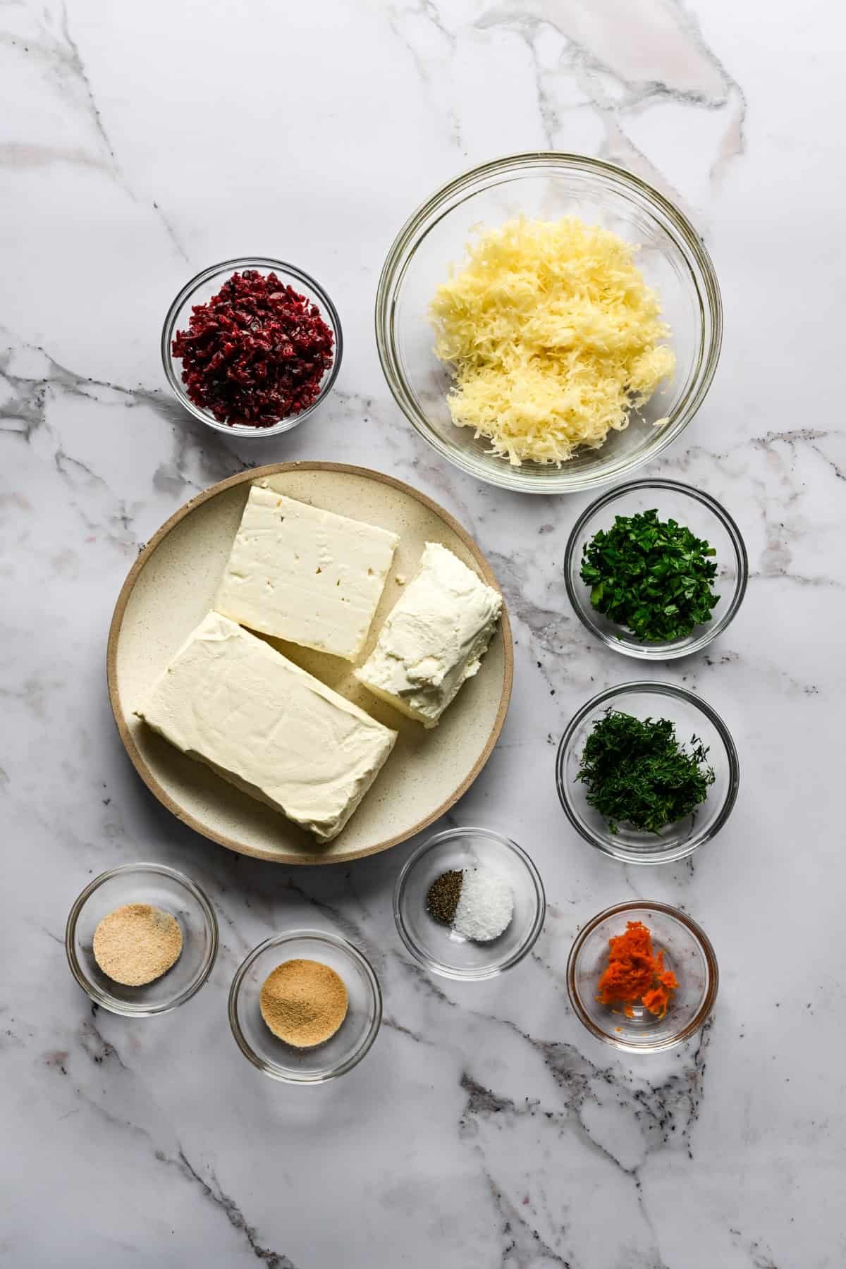 Bovenaanzicht van ingrediënten om zelfgemaakte kerstboomkaasbal in kleine kommen te maken.