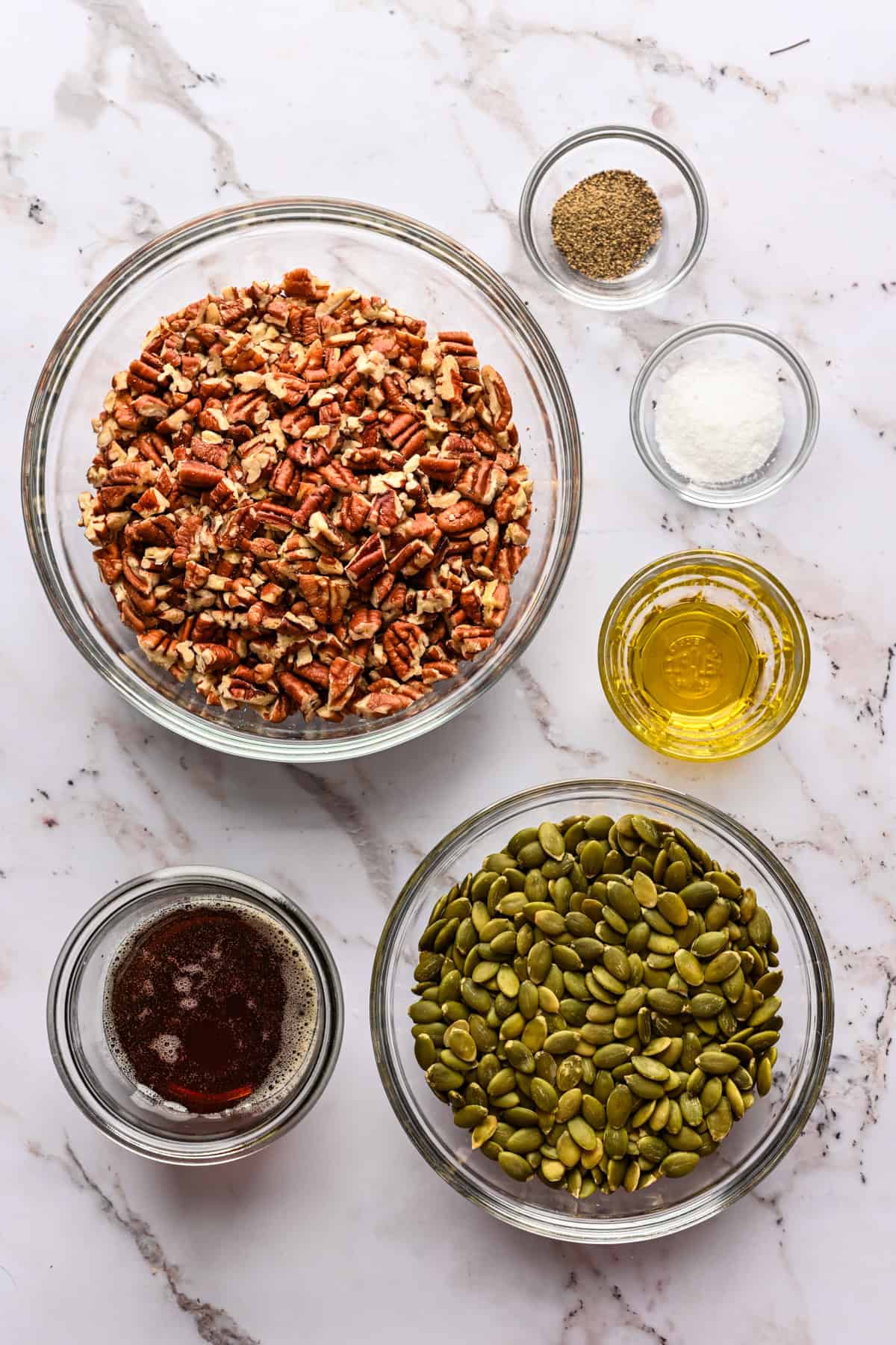 bovenaanzicht van ingrediënten voor pecan pepita bros in kleine kommen.