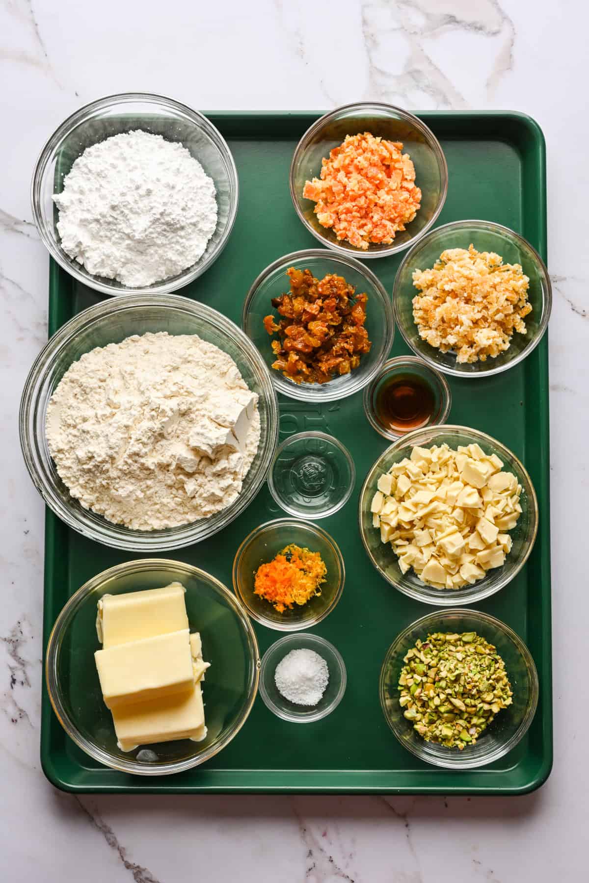 Bovenaanzicht van ingrediënten voor panettone-koekjes in kleine glazen kommen.