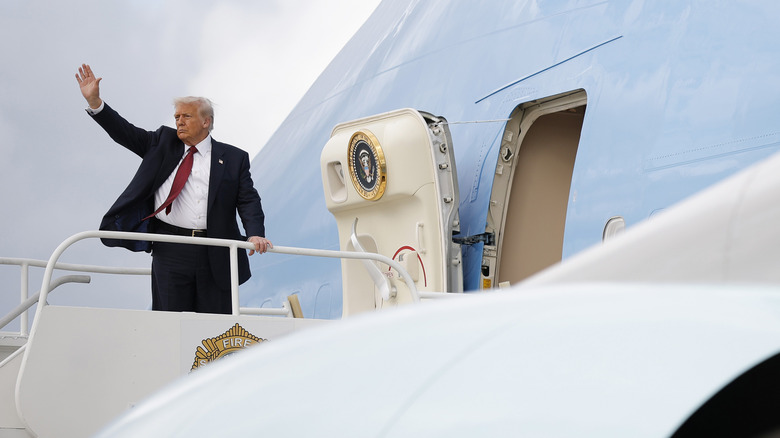 Donald Trump bovenaan de trap van Air Force One, zwaaiend met zijn hand.