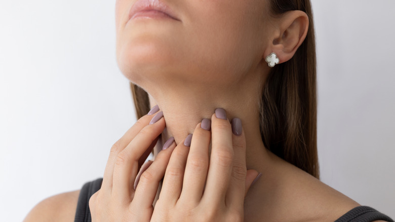 vrouw die de locatie van de schildklier aanraakt