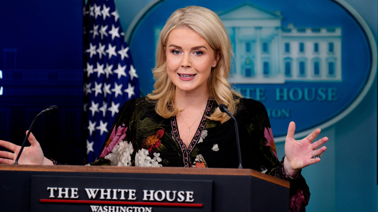 Karoline Leavitt gebaart met beide handen achter het podium in de perskamer van het Witte Huis