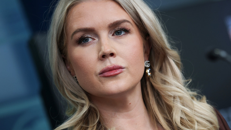 Een getitelde hoekfoto van Karoline Leavitt achter een microfoon.