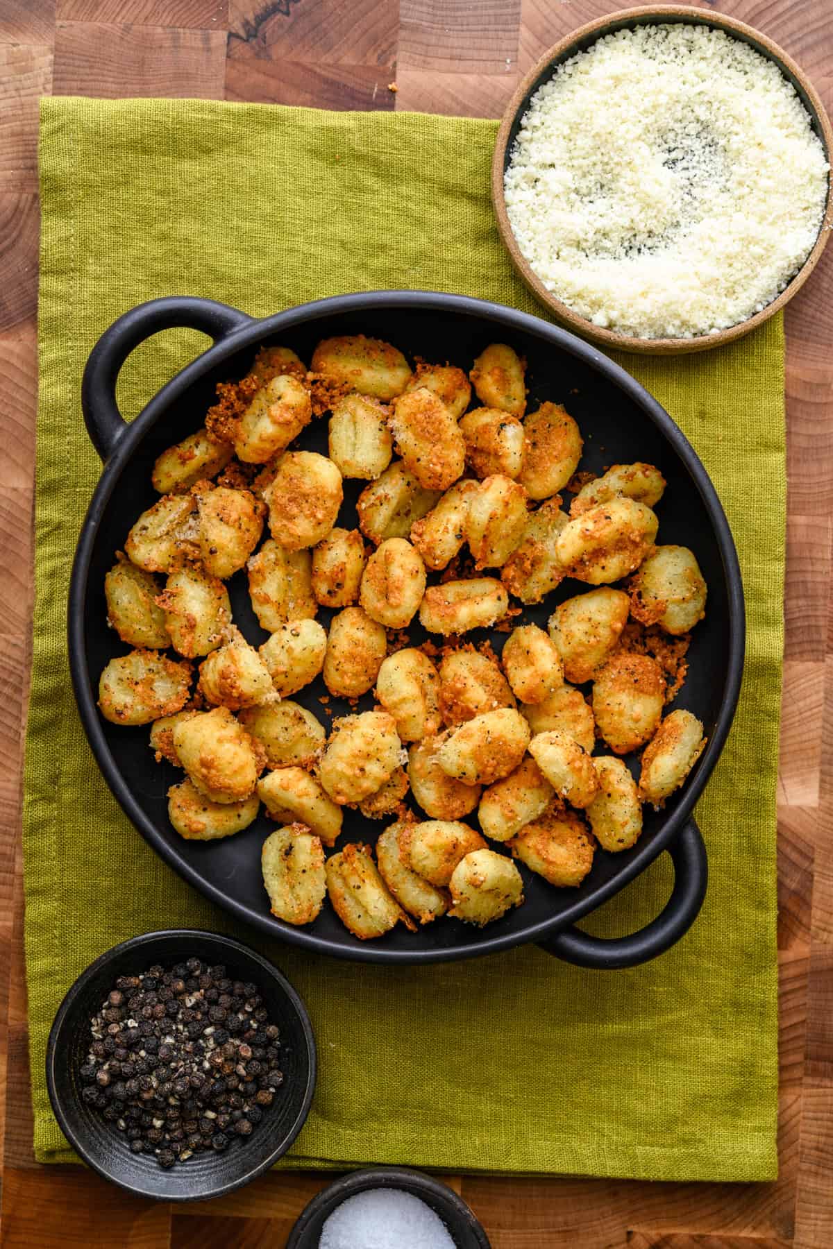 Krokante cacio e pepe gnocchi uit de luchtfriteuse in een zwarte kom.