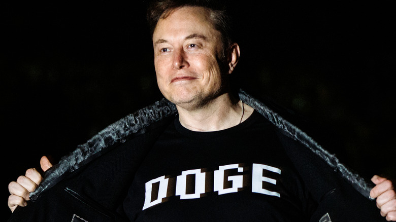 Elon Musk in het donker, terwijl hij zijn jas openhoudt om een ​​te onthullen 