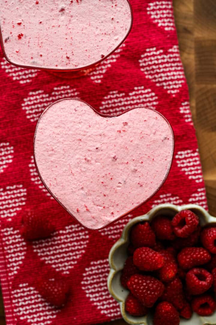 Bovenaanzicht van frambozenmousse in een hartvormig glas.