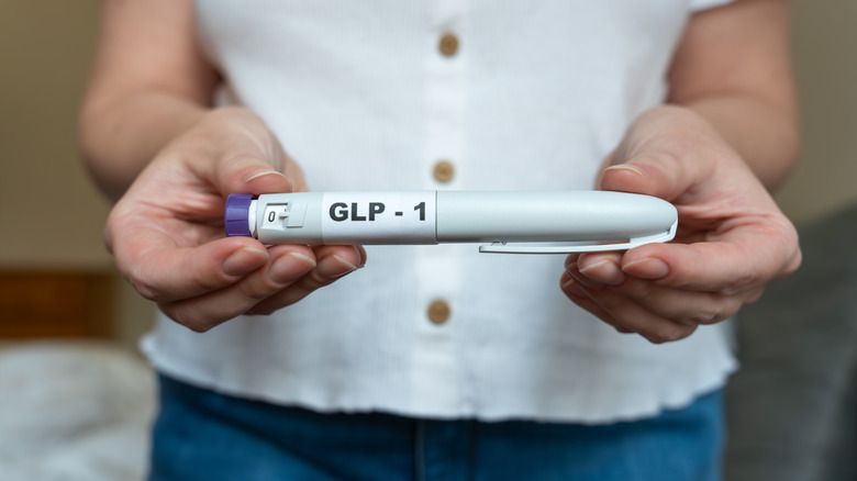 vrouw die een injectorpen vasthoudt voor een GLP-1-medicijn