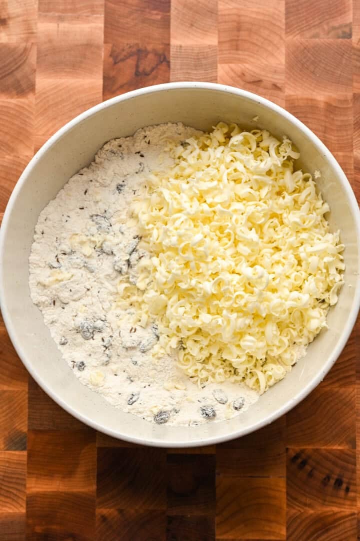 Geraspte boter bovenop het droge mengsel voor Ierse sodabroodscones vóór het mengen. 