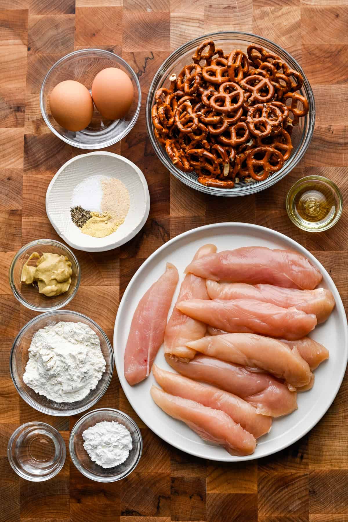 Bovenaanzicht van malse ingrediënten voor kip, waaronder kip, pretzels en kruiden.