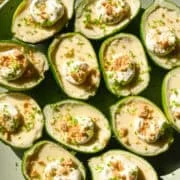 Bovenaanzicht van limoenpossets gegarneerd met slagroom en graham crackerkruimels op lichtgroene plaat.