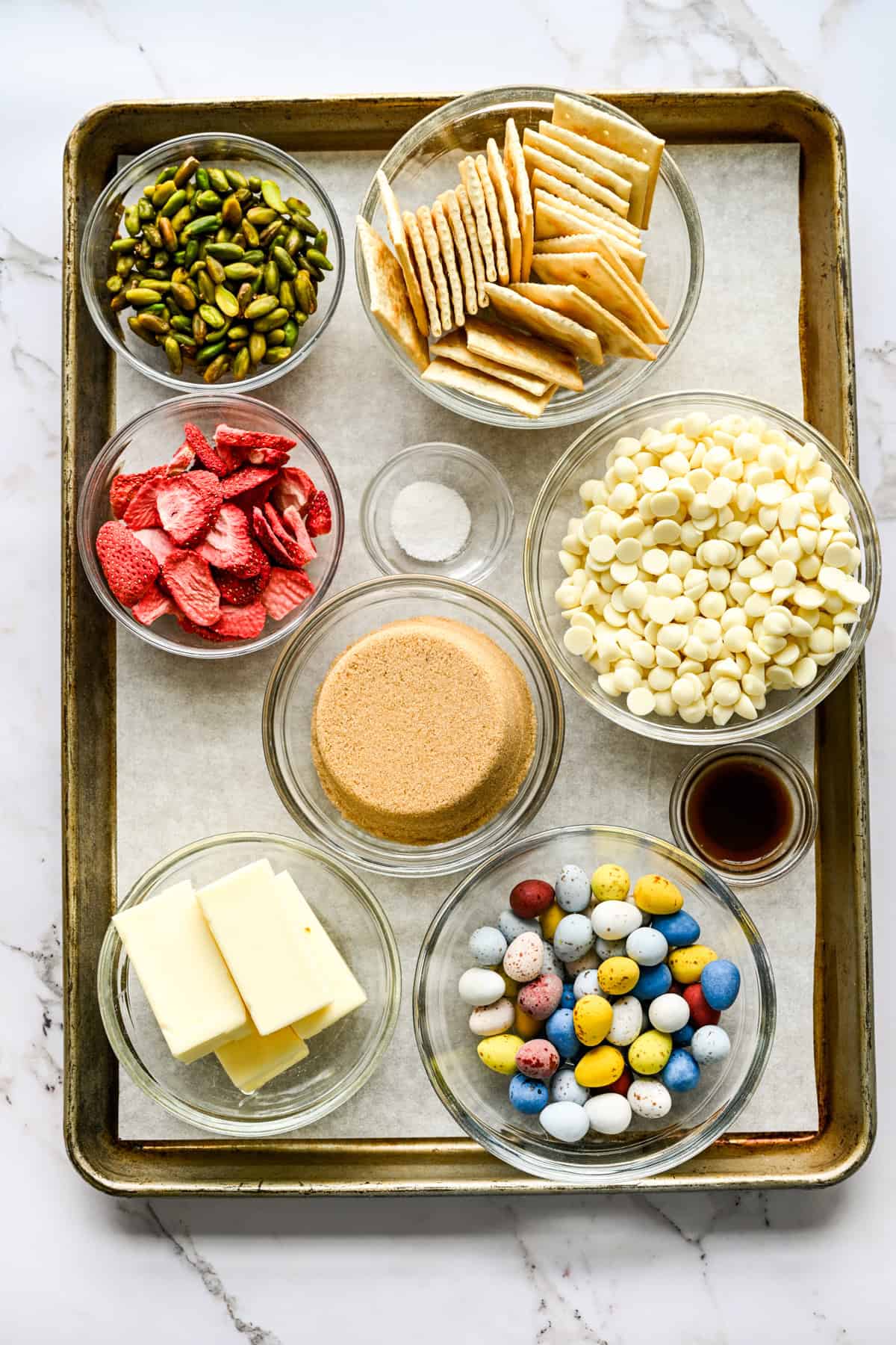 Bovenaanzicht van ingrediënten voor paaskoekjes, waaronder witte chocoladestukjes, boter en suiker.