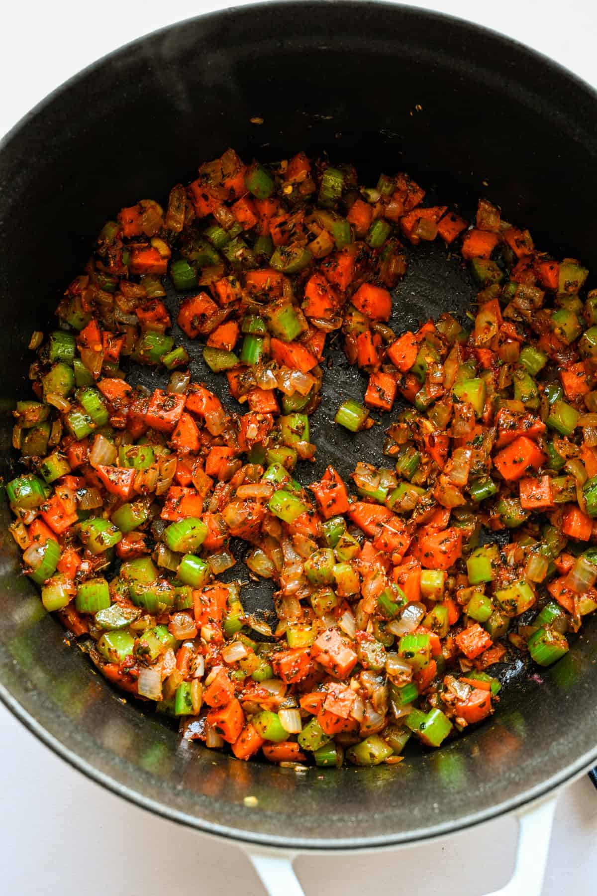 Tomatenpuree en kruiden toegevoegd aan de groenten in de pot.