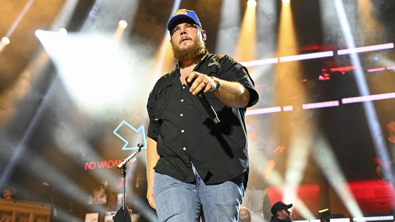 Luke Combs houdt een microfoon vast en loopt het podium op