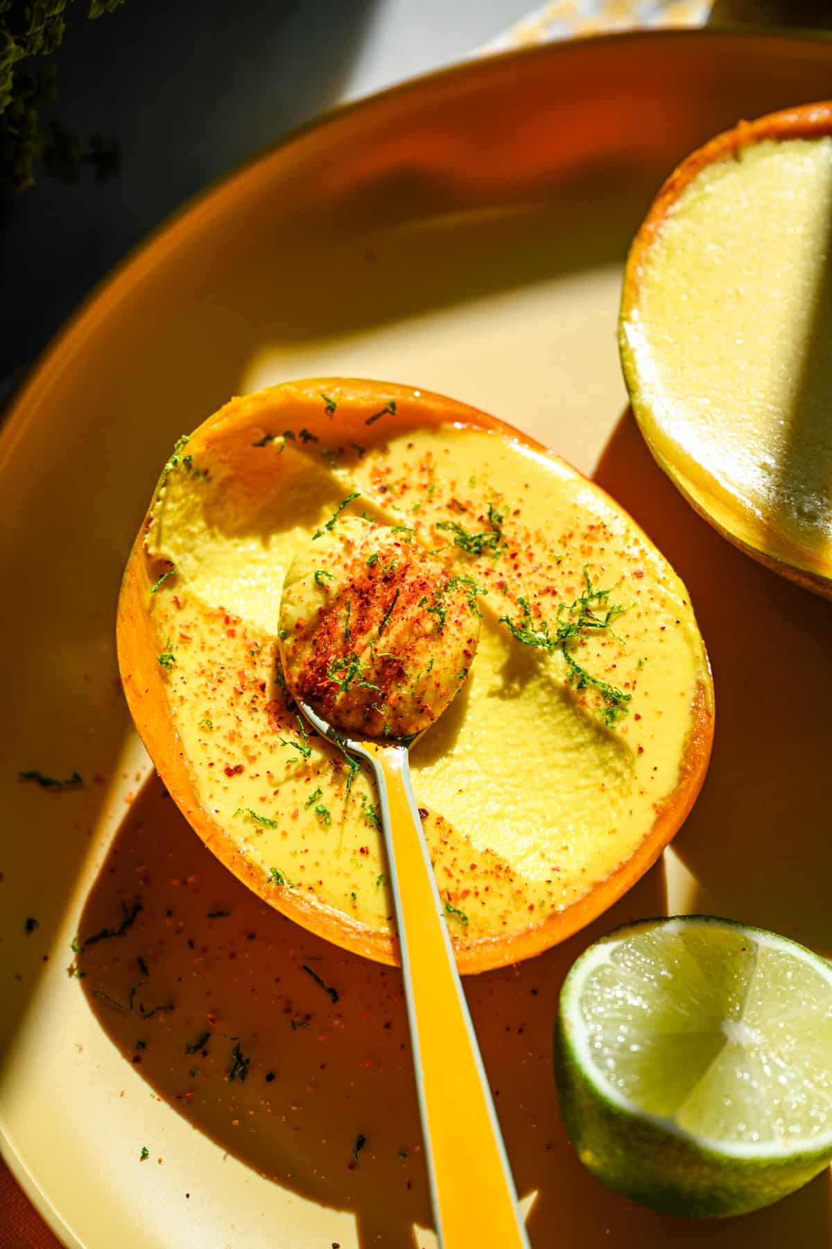 Bovenaanzicht van mango posset met tajin en limoenschil.