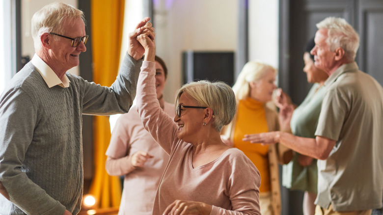 Senioren glimlachen en dansen terwijl ze genieten van activiteiten in een bejaardentehuis