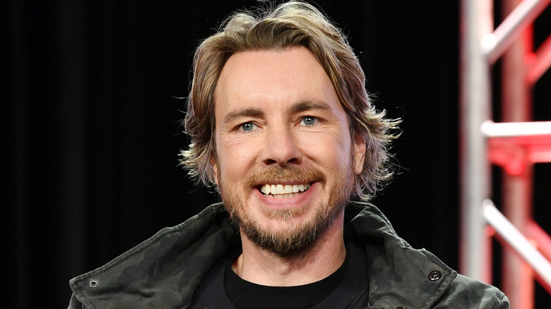 Dax Shepard geeft een grote glimlach aan een publiek tijdens een evenement