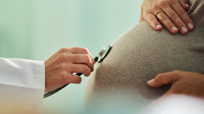 dokter luistert naar de maag van een zwangere vrouw