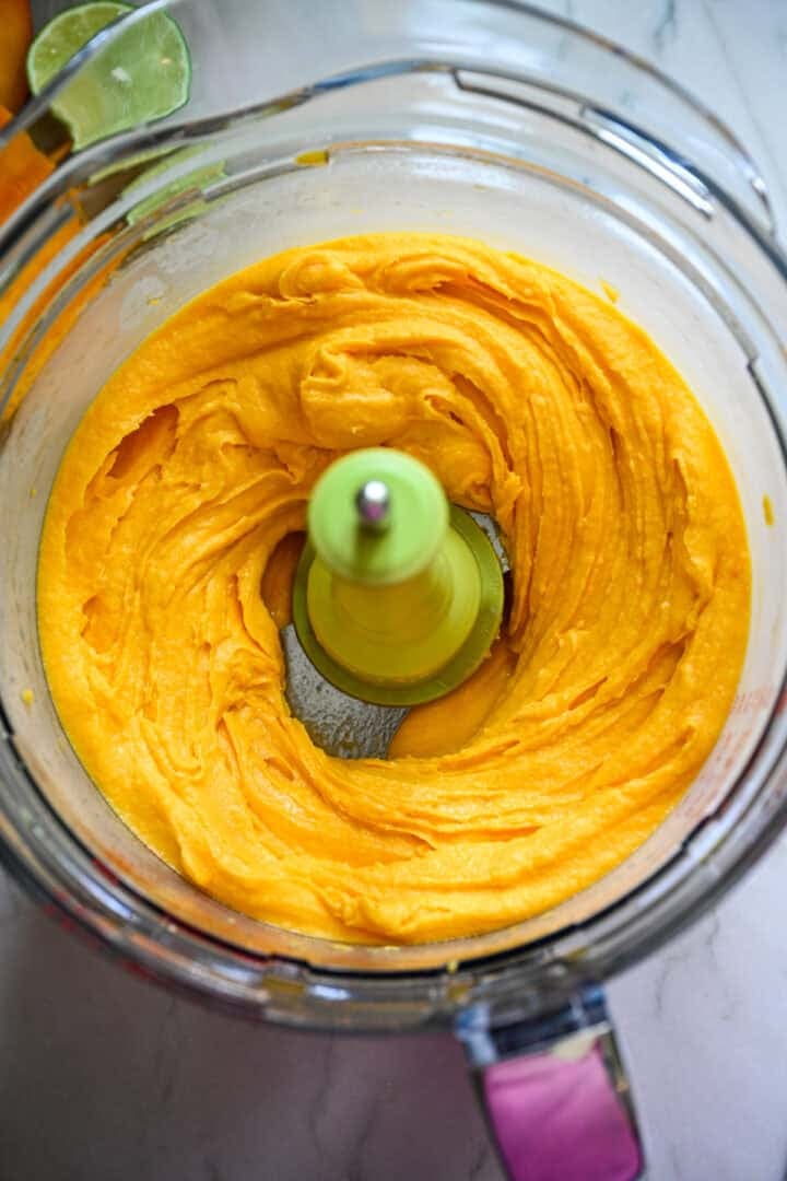 Mangosorbetingrediënten in een keukenmachine na het mengen.