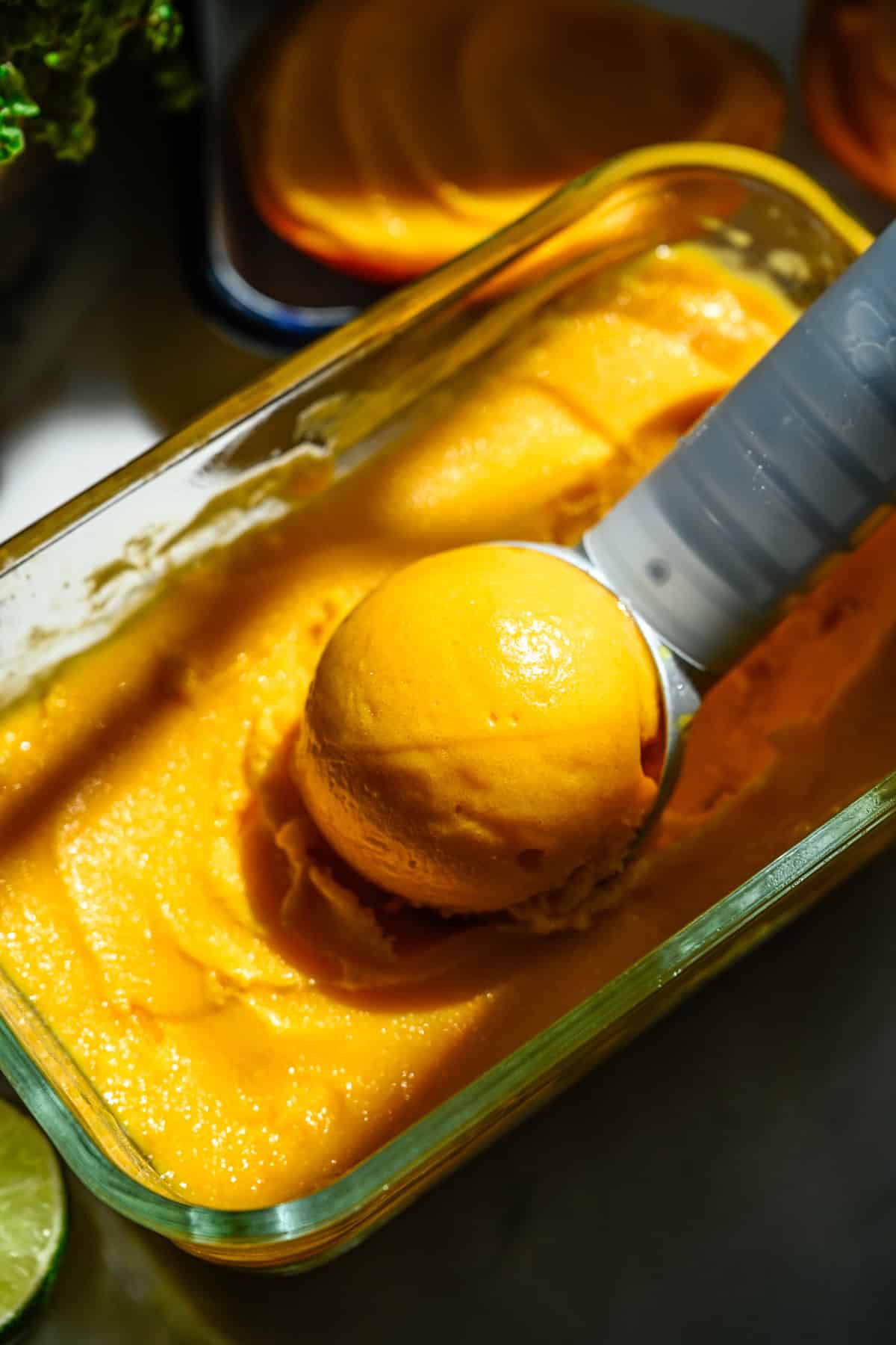 Close-up van een bolletje mangosorbet in een bakje sorbet.