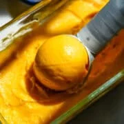 Close-up van een bolletje mangosorbet in een bakje sorbet.