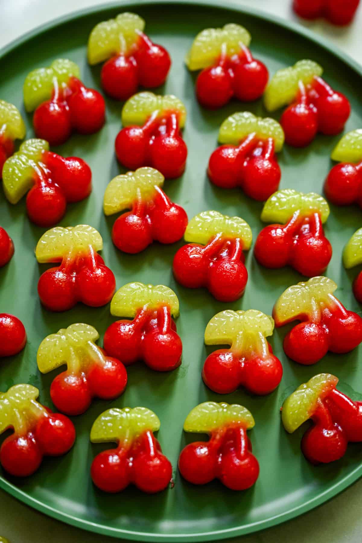 Bovenaanzicht van verschillende kersengummies op een groene plaat.