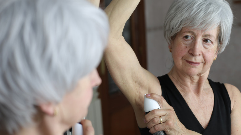 Senior vrouw die deodorant aanbrengt in de badkamer